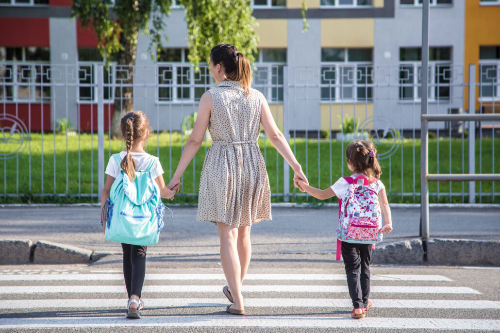 Woman and children holding hands as they use a pedestrian crosswalk.