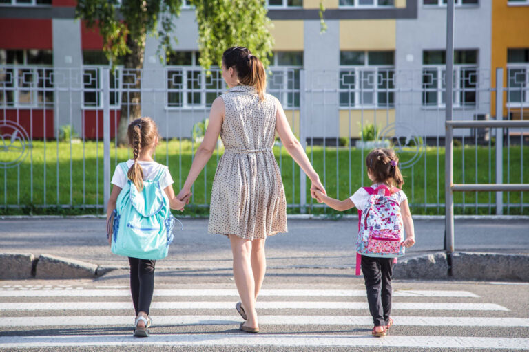 Woman and children holding hands as they use a pedestrian crosswalk.